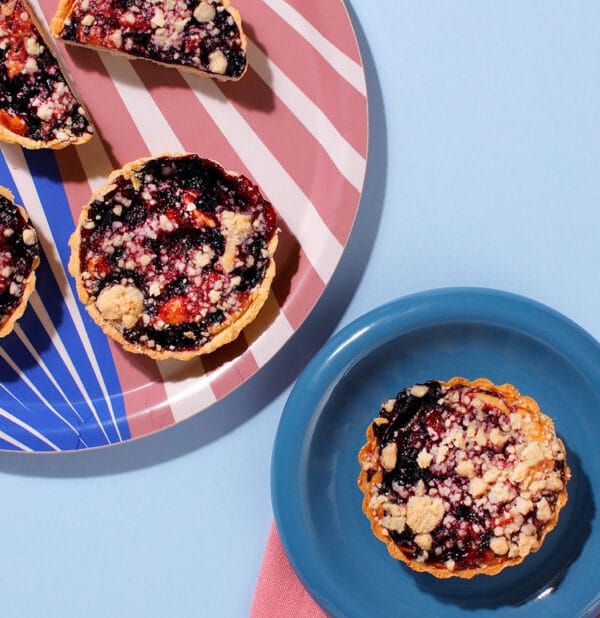 Top view of Blueberry and Lemon Muffin Tart with lemon sponge and blueberries on blue background.