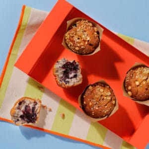 An overhead view of our scrumptious Blueberry Muffins in a presentation box. Two of the muffins have been half eaten.