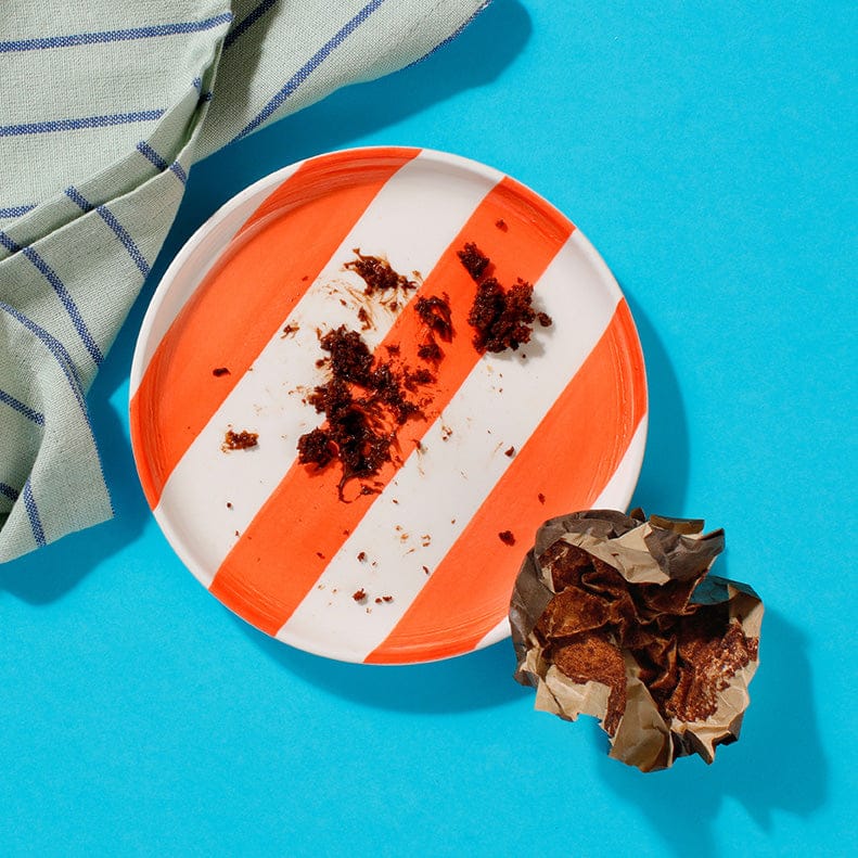 An empty plate except for a few crumbs and a wrapper from one of our Chocolate Muffins.