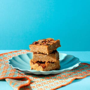 Maple and Pecan Flapjack square on blue plate with visible layers of oats, maple syrup and pecans.