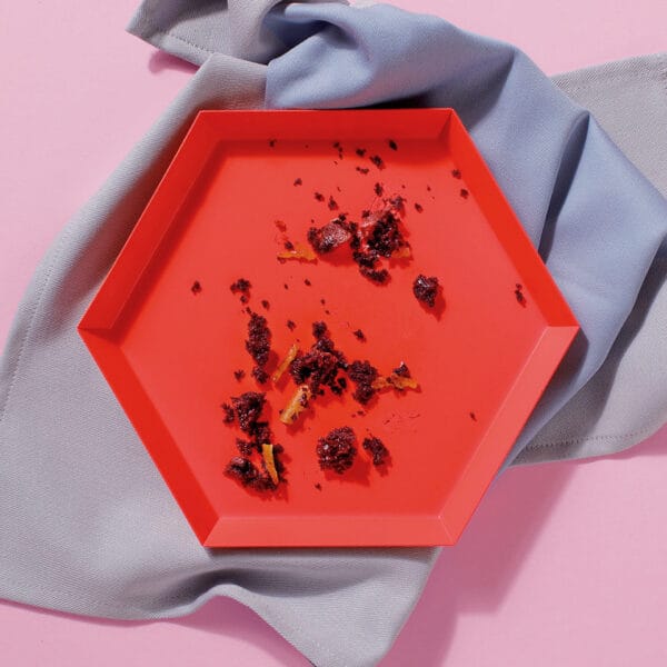 Ab empty plate viewed from overhead containing only crumbs from o slice of our vegan chocolate joy tray cake - baked especially for wholesale to coffee shops.