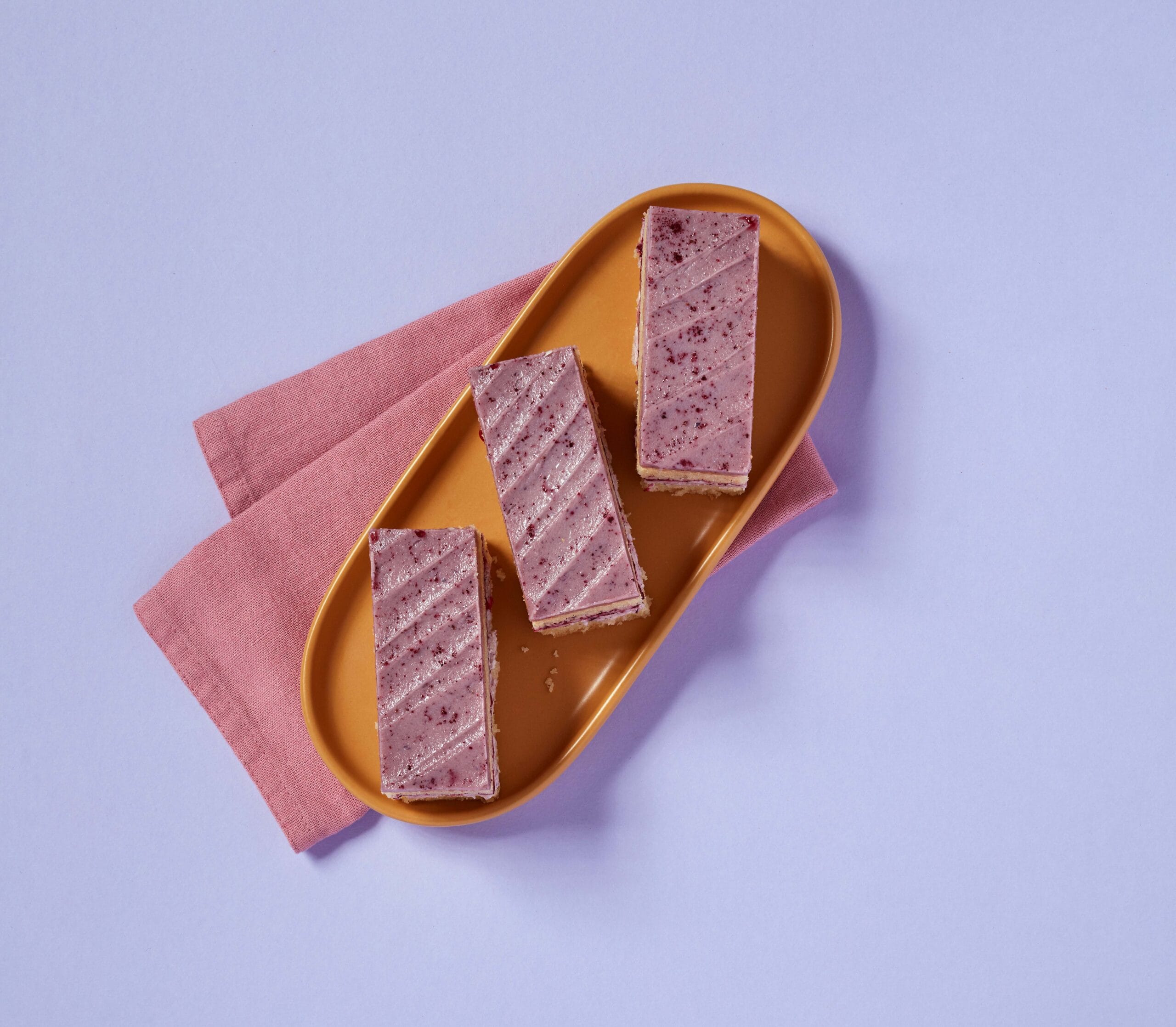 Slices of Blackberry and Mascarpone Traycake on a plate with a pink napkin.