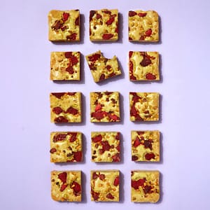 A full tray of Cake Club Pistachio and Raspberry Blondie on a purple background.