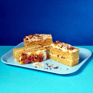 Passionfruit and Coconut Traycake slices on a blue tray with a deep blue background.