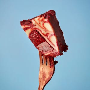 A slice of mouth-watering Red Velvet Brownie from Cake Club held aloft on a fork.