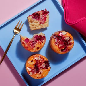 Mini Cherry Bakewell portions displayed on a blue tray against a red backdrop.