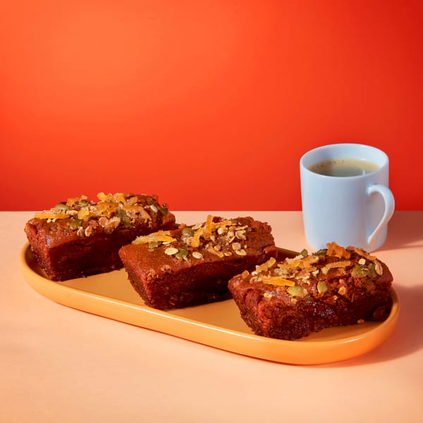 Vegan Sticky Ginger and Lemon Mini Loaf slices on yellow platter with coffee cup showing caramelised lemon topping.