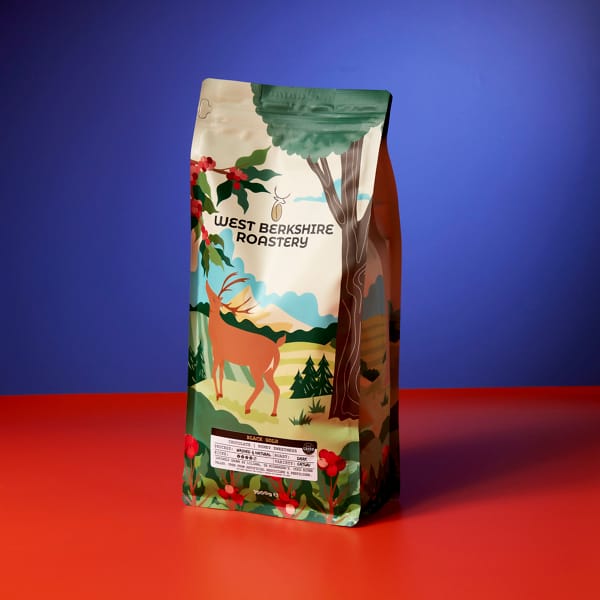 A 1kg bag of West Berkshire Roastery Black Gold coffee beans on a blue and red contrasting background
